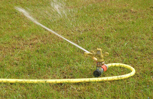 copper lawn sprinkler spraying water